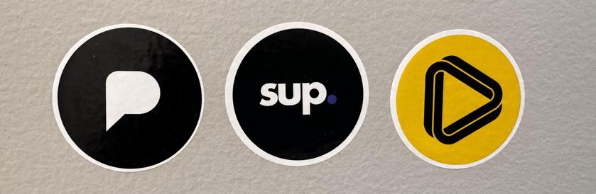image of 3 round stickers, the first is Pixelfed black logo with the white cutout, next is the sup logo with a black background and text "sup." that is white with indigo tinted period and the last sticker is Loops which is a yellow background with a black Loops logo
