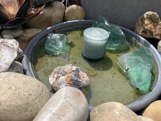 Schale mit Steinen, Glas und Wasser auf der Terrasse 