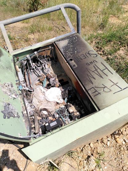 Ein ausgebrannter Stromkasten, darauf kann man mit etwas Fantasie noch entziffern: Free Hambi und Sündi.