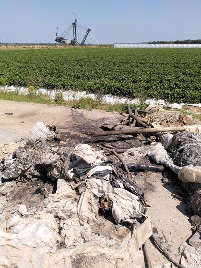 Verbrannte Überreste von Straßenblockaden. Im Hintergrund zu erahnen ein Schaufelradbagger.