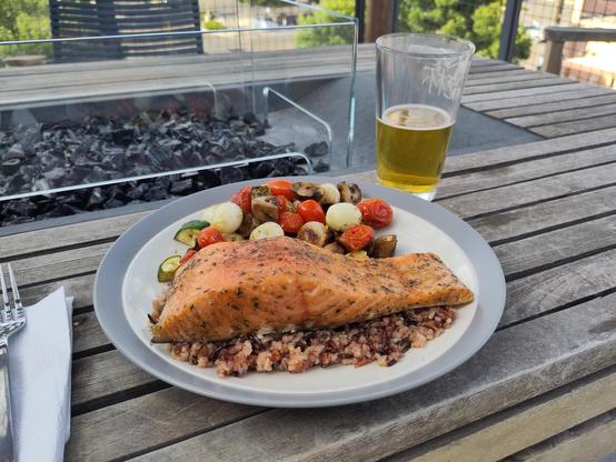 Cedar plank salmon on a bed of wild rice. The salmon is cooked to medium and seasoned with a rub of salt, black pepper, thyme, sage, and bourbon barrel smoked sugar. There is a side of grilled mixed vegetables. There is an IPA in view.