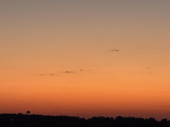 A nice gradation of an orange-red sunset with a tiny water tower on the horizon