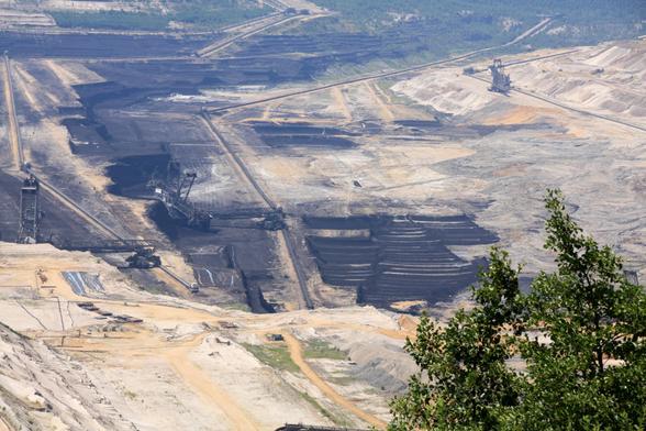 Zoom auf den schwarzen Grund des Lochs des Hambacher Tagebaus. Die Maschinen sehen wie Spielzeuge aus.