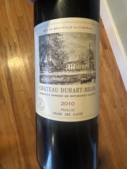 Front of bottle of red:  2010 Chateau Duhart-Milton Pauillac featuring a black and white illustration of the Chateau.

Scanned from image:

“MIS EN BOUTEILLE AU CHÂTEAU
CHATEAU DUHART-MILON
DOMAINES BARONS DE ROTHSCHILD ILAFTEI
2010
PAUILLAC
GRAND CRU CLASSE”