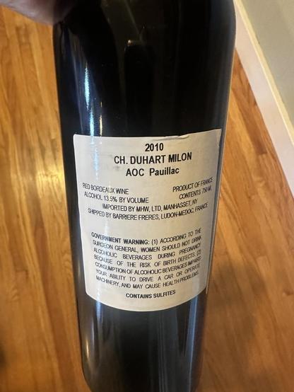 Back of bottle of red:  2010 Chateau Duhart-Milton Pauillac featuring a black and white illustration of the Chateau.

Scanned from image:

“2010
CH. DUHART MILON AOC Pauillac
RED BORDEAUX WINE
PRODUCT OF FRANCE
ALCOHOL 13.5% BY VOLUME
CONTENTS 750 V.
IMPORTED BY MH, LTD, MANHASSET, NY SHIPPED BY BARRIERE FRERES, LUDON-MEDOC, FRANCE GOVERNMENT WARNING: (1) ACOORDING TO THE SURGEON GENERAL, WOMEN SHOULD NOT DRINK ALCOHOLIC BEVERAGES DURING PREGNANCI BECAUSE OF THE RISK OF BIRTH DEFECTS A CONSUMPTION OF ALCOHOLIC BEVERAGES IMPARS YOUR ABILITY TO DRIVE A CAR OR OPERATE MACHINERY, AND MAY CAUSE HEALTH PROBLEMS
CONTAINS SULFTES”