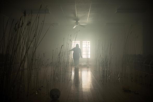 An actor performing a theatre peace on stage in a smoky atmosphere.