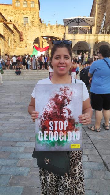 Una mujer, en la Plaza Mayor de Cáceres, sosteniendo un cartel con el lema STOP GENOCIDIO.