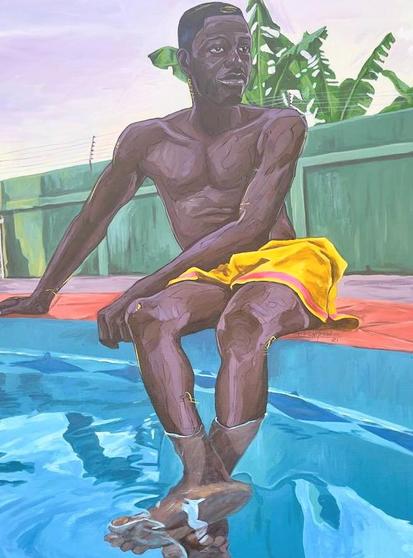 A young man dangling his feet on the side of a pool with yellow swim suit shorts and a orange towel underneath him painting 