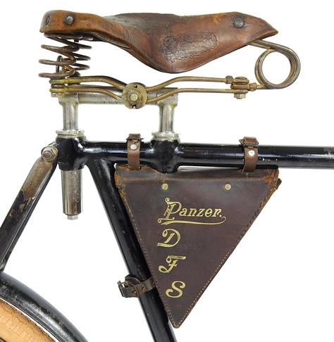 Ausschnit eines Fahrrads mit altem Ledersattel und zweifacher Befestigung des Sattels. Darunter eine Rahmen-Ledertasche mit dem Aufdruck "Panzer DFS"
