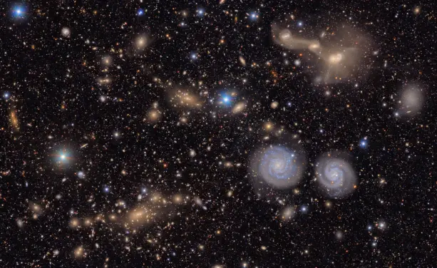 Visible are two prominent spiral galaxies (lower right), three merging galaxies (upper right), several groups of distant galaxies, many stars in the Milky Way and more.