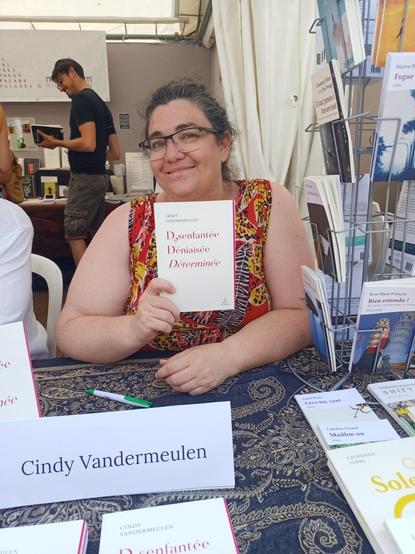 Photo de Cindy Vandermeulen avec le livre Désenfantée Déniaisée Déterminée paru chez Abrapalabra éditions sur le stand au marché de la poésie de Paris
