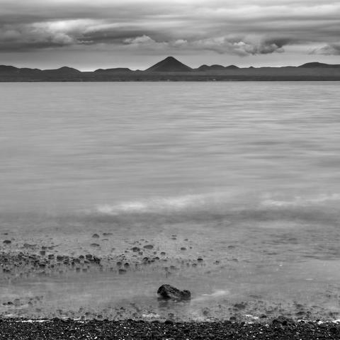 A black and white picture of the mountain Keilir as seen from the beach at Alftanes. Its a long exposure picture so the sea is smoothed out.