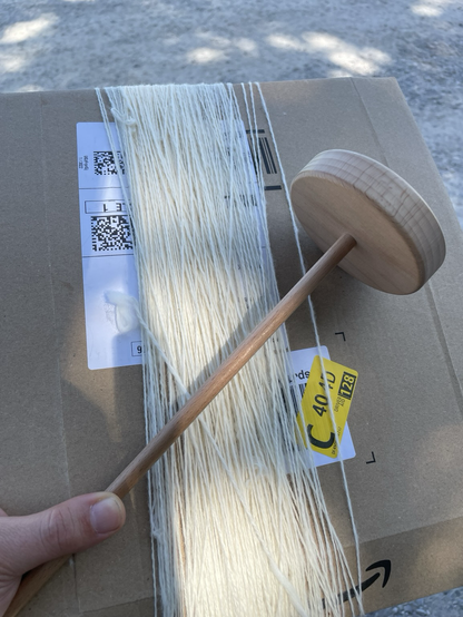 Weißes Garn auf Pappumschlag gewickelt, Handspindel