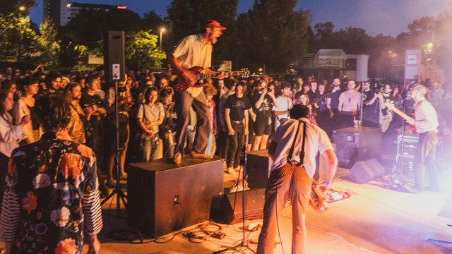 guitarist with a crazy facial expression standing on the PA about to jump down