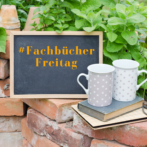 kleine Schiefertafel auf Mauer, zeigt den Schriftzug #FachBücherfreitag, daneben stehen 2 gepunktete Bechertassen auf 2 Büchern