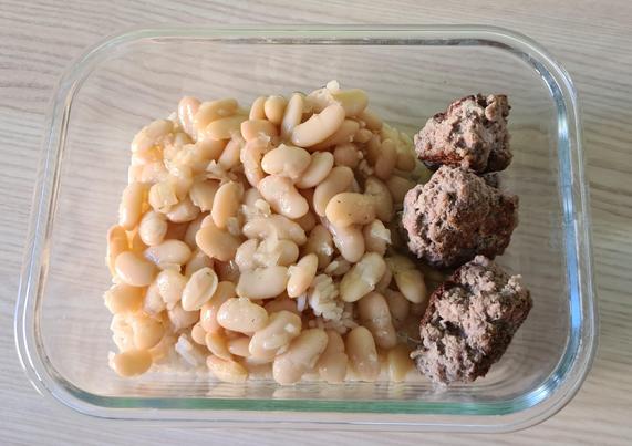 Eine Glasschale voll Essen. Rechts drei Fleischbällchen, links weiße Bohnen auf Reis.