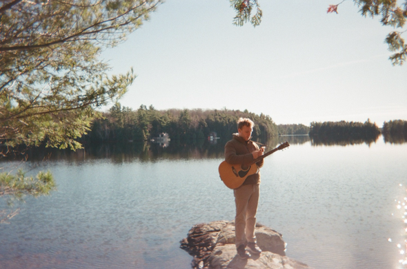 The M.A.S. Project stands on a rock on a lake 
