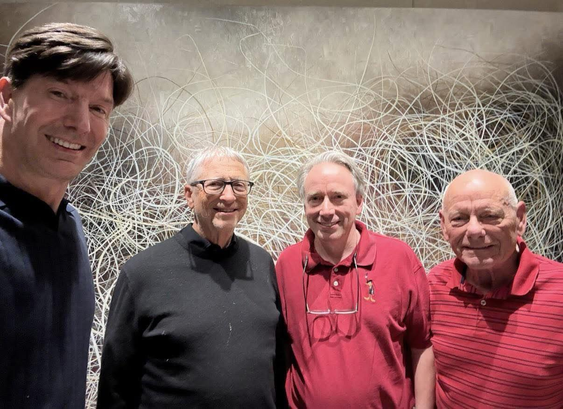 There are four people posing for a photo, with Bill Gates (black shirt) and Linus Torvalds (red shirt) in the center. We are not sure who the other two people are.