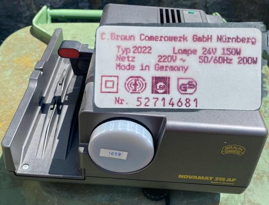 The image displays a Braun Novamat 315 AF light meter, featuring a control dial and a label with specifications, including its model number, power requirements, and manufacturing details.