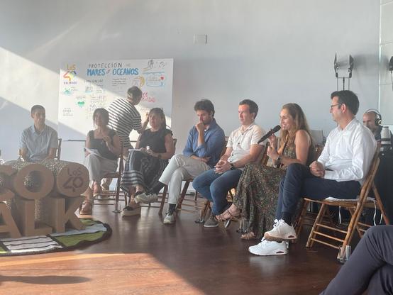 Asistentes al evento realizan aportaciones verbales al programa de radio Los 40, mientras Pernan va dibujando lo que dicen en un mural situado al fondo de la estancia.