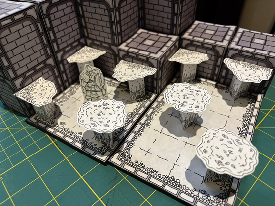 A photo of a black-and-white papercraft dungeon scene. Walls along the back surround two dungeon tiles where a barbarian character is standing. Several "water surface" standees are placed to make it look like there is a surface of water in the room.