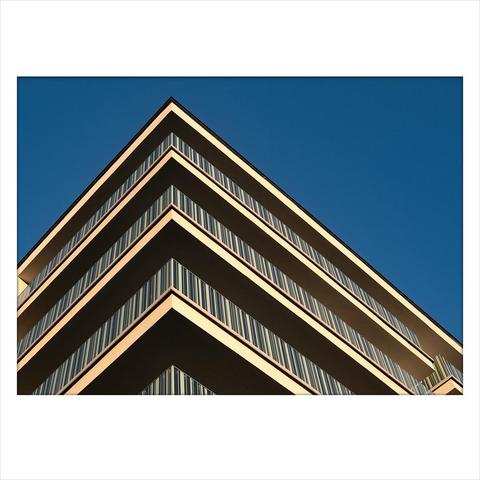 There's a modern  house in the picture, which I photographed from the corner, looking up. There are striped balcony railings all around, and at sunset the whole picture became very flat, as if the floors were just two-dimensional triangles on top of each other.