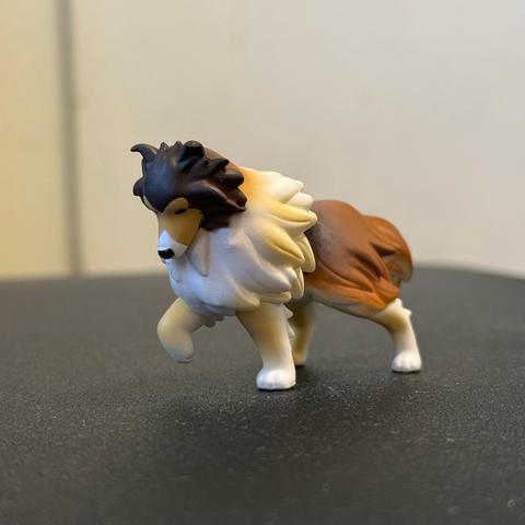 A small figurine of a Sheltie fighting to move forward against the wind.