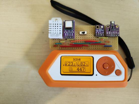 Flipper Zero with DIY Modul with four sensors attached. 
Sensors from left to right: DHT22, SCD-40, BME280, BME680.
The Flipper screen shows the sensor name on top, SCD-40, and below measurements from the SCD-40 sensor.
The Measurements are, temperature 23.2, humidity 82% (which is wrong) and CO2 ppm 447
