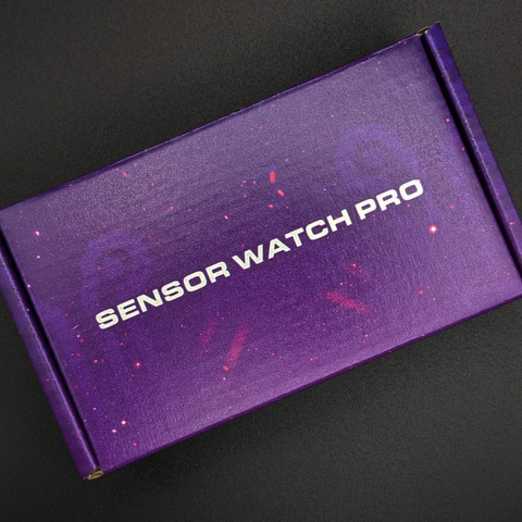 Top view of a purple rectangular cardboard box on a black background. The box has a starry vaporwave aesthetic and has SENSOR WATCH PRO written at its center.