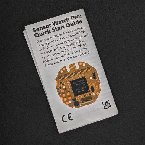 A foldable paper manual or Quick Start Guide for the Sensor Watch Pro with a picture of the PCB  on the paper.