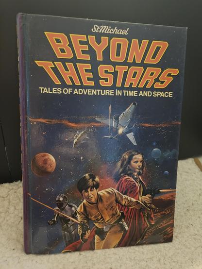 The 1983 book published by St Michael Beyond the Stars: Tales of Adventure in Time and Space sitting on my cat's blanket on my desk
