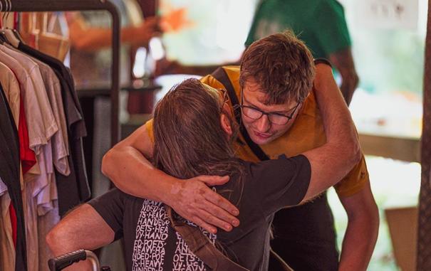 A man embraces another man in a clothing store, showcasing a moment of friendship and support.