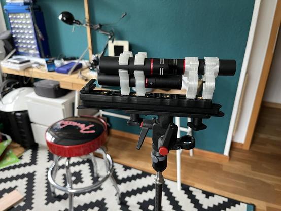 Color Foto of a microphone stand with several mics inside 3-D printed clips in a Double-Mid-Side setup. In the background you can see a somewhat messy workplace with a stool, a workbench, a desklamp and a petrol blue wall.