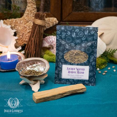 The contents of our exclusive "Sea Witch Abalone Cleansing Set" product are arranged on a velvet surface. They include an abalone shell to use as an incense  burner, a stick of Palo Santo wood, and a pouch of Sacred Waters Herbal Blend containing rosemary, peppermint, and lemon myrtle. This is an exclusive product from Inked Goddess Creations.
