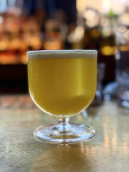 A cocktail in a low goblet. The cocktail is golden in color and has blended scotch whisky and arak, a combo which was amazing. 