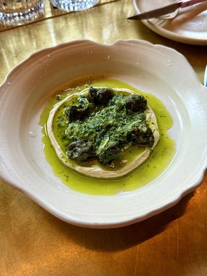 A plate of escargot on a bed of hummus. The snails are covered in a green herb and garlic sauce. I can’t stop thinking about how good this was. 