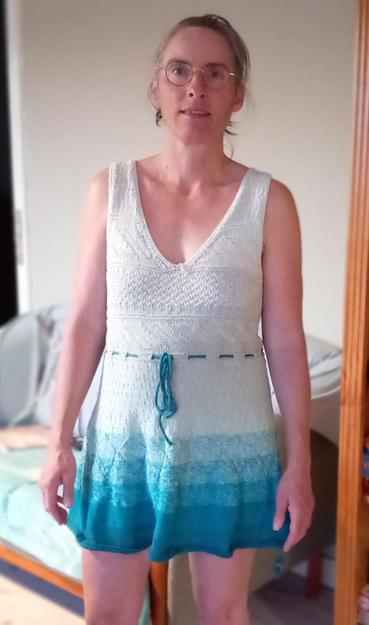Femme portant une robe courte  tricotée en coton dans un dégradé turquoise à blanc,  vu de face.