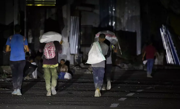 Des Palestiniens reviennent d'un point de distribution d'aide alimentaire mis en place par la Fondation humanitaire de Gaza (GHF) sur la route de Salaheddin, au camp de réfugiés de Nousseirat, dans le centre de la bande de Gaza, le 24 juin 2025.