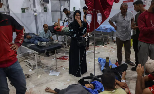 Une Palestinienne au milieu de personnes blessées par des tirs israéliens à un point de distribution d'aide alimentaire de la Fondation humanitaire de Gaza (GHF), prises en charge à l'hôpital Al-Awda du camp de réfugiés de Nousseirat, dans le centre de la bande de Gaza, le 24 juin 2025.
