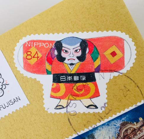 Japanese 84-yen stamp featuring a colorful Kabuki actor illustration.