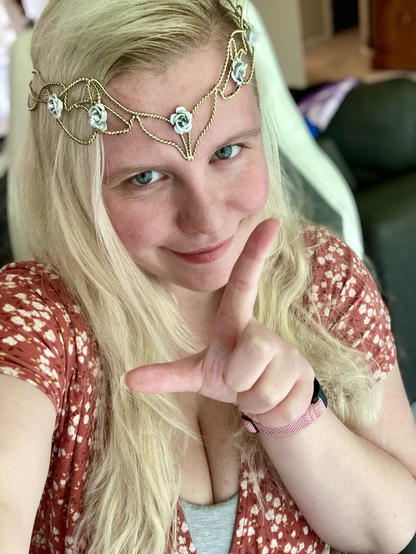 Selfie of Queen in a floral dress holding up her hand in an L