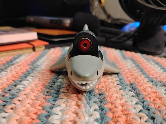 Front view of an image of a laser pointer in the shape of a shark with laser beam in the vein of Dr. Evil from Austin Powers.