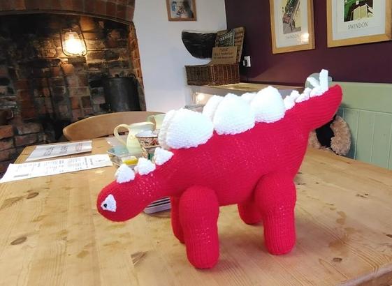 A knitted red stegosaur with a double row of white spines / plates all the way down its back to its tail. An amazing new handmade toy that lives at the Richard Jefferies Museum, lovingly created by Doreen, our cafe volunteer Terry's mum!