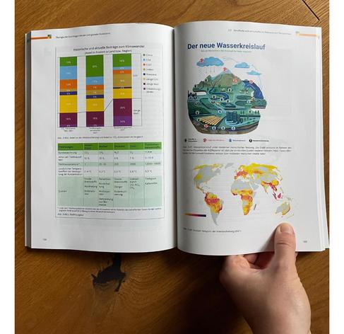 Aufgeklapptes Schulbuch mit einer Graphik “Der neue Wasserkreislauf”, der den Einfluss des Menschen zeigt. 