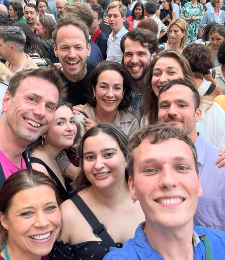 Selfie van een groepsfoto met zo’n 10 personen, maar daarachter nog veel met anderen. In het midden burgemeester Femke Halsema.