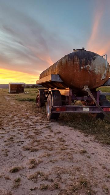 Breckenheimer Weg (Greater Wiesbaden, Germany) at dusk. Farm scene with fertilizer tank on fallow field with pastel streaks from fading sunlight staining the sky.