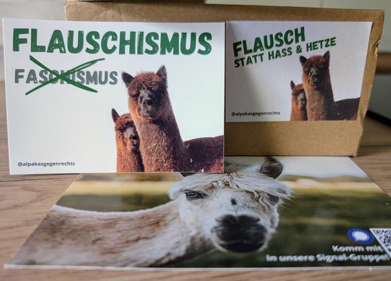 Auf einer Küchenarbeitsplatte liegt eine Postkarte, auf der ein Alpaka abgebildet ist.
Dahinter aufgestellt ein Aufkleber mit zwei Alpakas. Darauf steht "Flauschismus" und darunter das durchgestrichene Wort "Faschismus".

Dahinter ein Karton mit einem Aufkleber, der ebenfalls zwei Alpakas zeigt. Darauf steht "Flausch statt Hass und Hetze".

Alles in einem Paket von @webertalalpakas & @alpakasgegenrechts