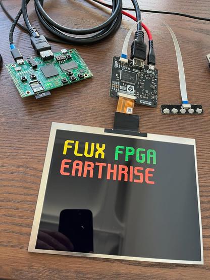 ULX3S FPGA dev board connected to 1024x768 LCD panel via TMDS to LVDS driver board. The LCD panel is displaying "FLUX FPGA EARTHRISE" in an angular font.