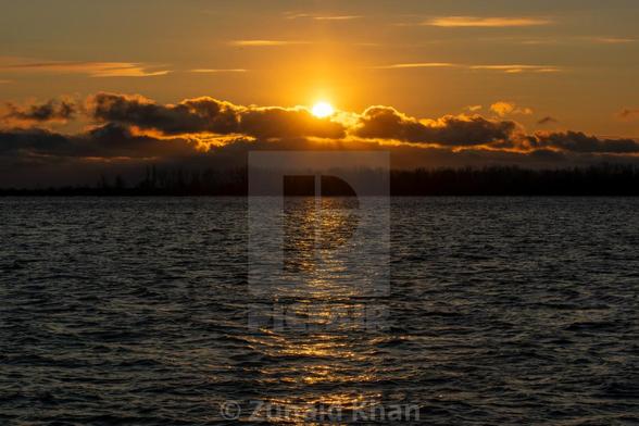 Sunrise over the Toronto Islands, with sunlight reflecting on Lake Ontario.