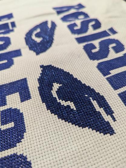 Close up of angry eyes in sparkly, dark blue thread.